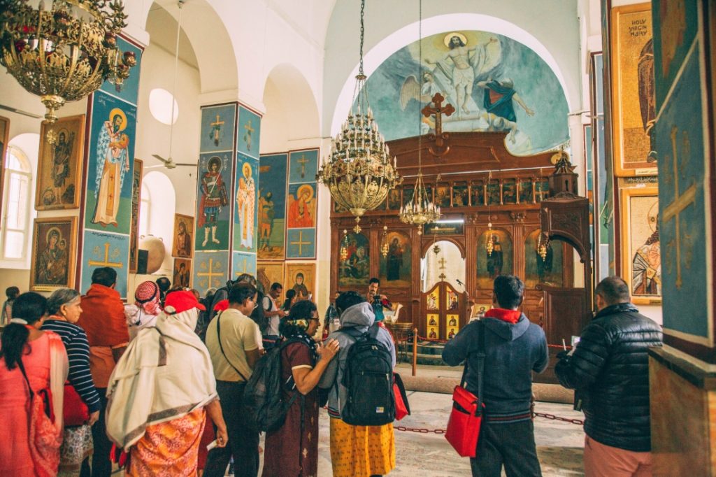 A group of people standing inside a St George Church, Jordan.