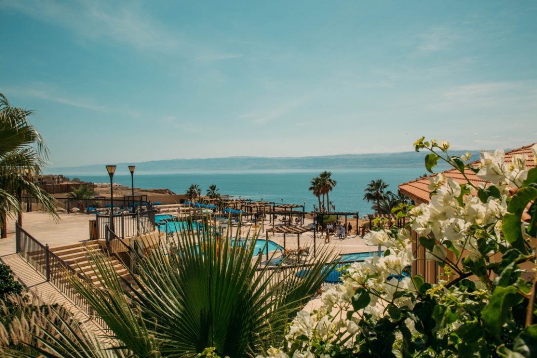 A view of pools and beautiful plants at a Dead Sea Resort with the Dead Sea in the background