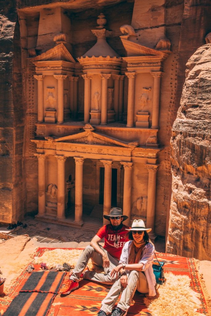 A couple posing on a rug in front of the Treasury in Petra, Jordan