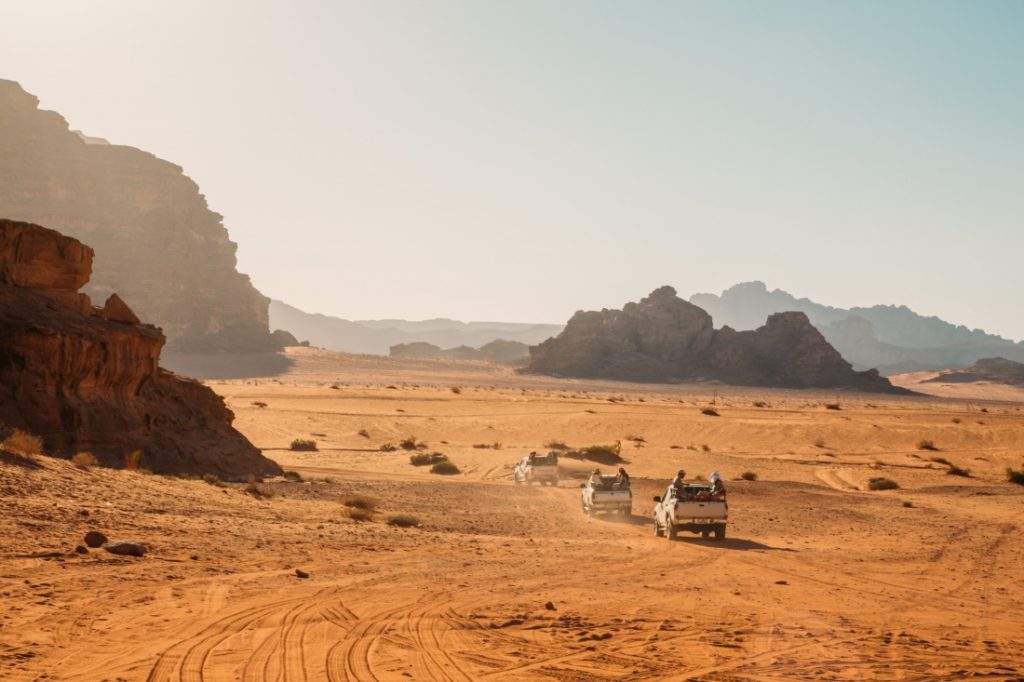 A jeep drives through the desert in wadi rum.