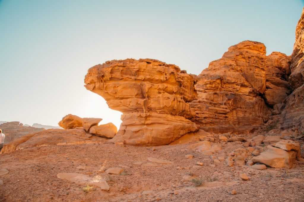 A towering rock formation pictured against a crystal clear blue sky in the Wadi Rum desert.