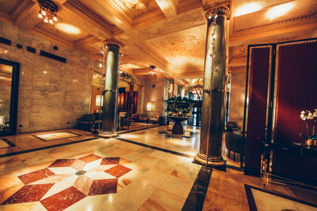 The Metropol Hotel lobby -- floor to ceiling marble tiles and an ornate marble floor, floor to ceiling pillars, and classic decorations.