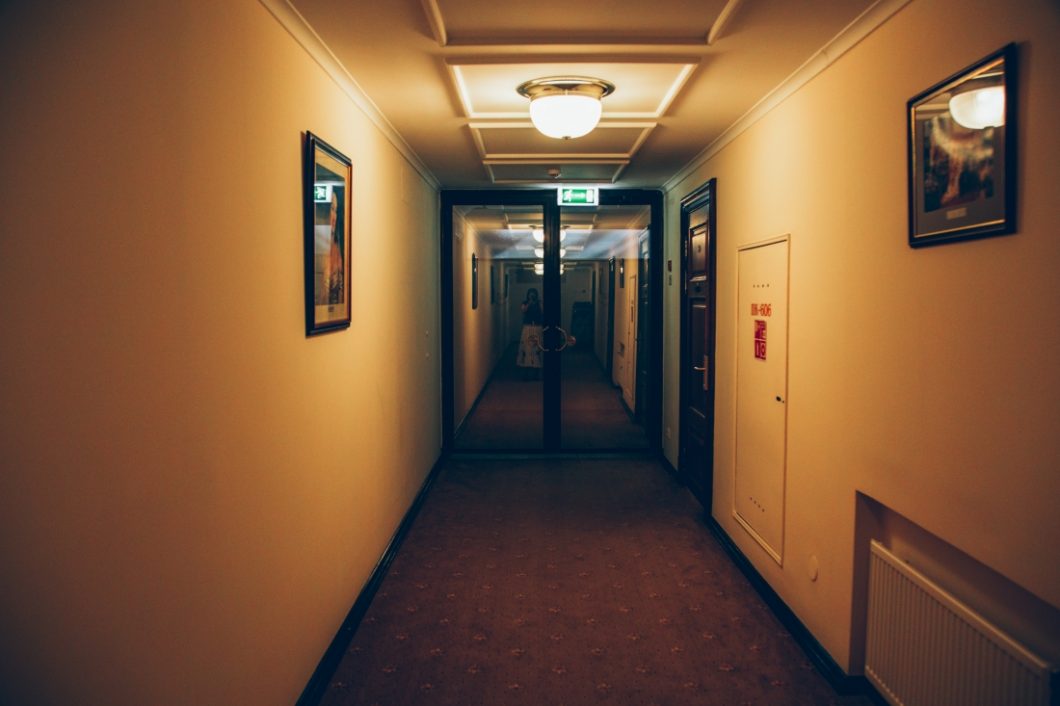 A dimly lit hallway on the 6th floor of the Metropol Hotel, looking towards double glass doors.
