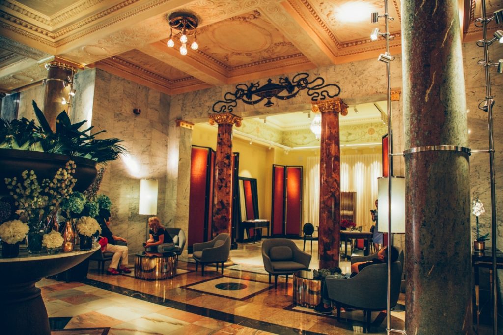 An interior image of the Metropol Hotel lobby, featuring marble floor to ceiling tiles and curtains in every doorway.