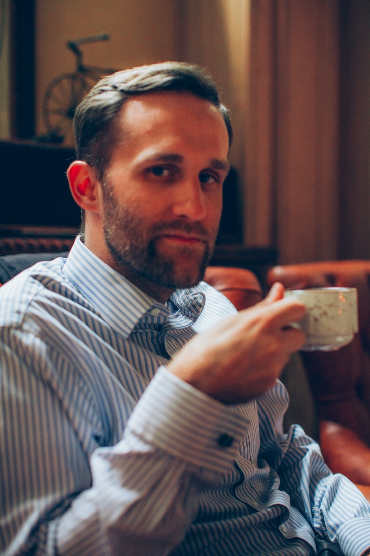 A man is seated inside the Bolshoi theater, ready for a performance, enjoying a cup of tea.