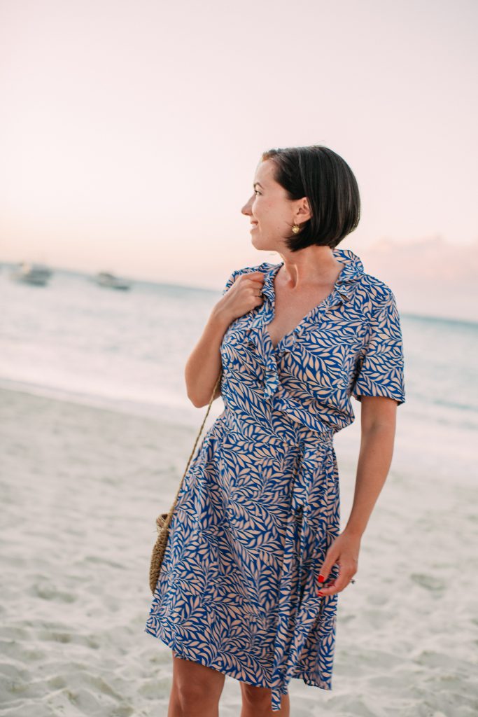 Lindsey wearing a blue and tan silk wrap dress on the beach as a resort evening look for the Sandals dress code