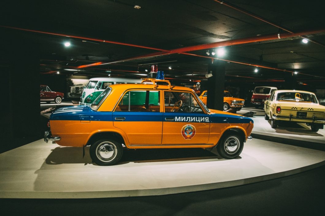 A vintage yellow and blue LADA VAZ 2103, once used as a police car, with an old municipal decal on the side door. This vintage car is on display at the Heydar Aliyev Center's Classic Car Exhibit in Baku, Azerbaijan