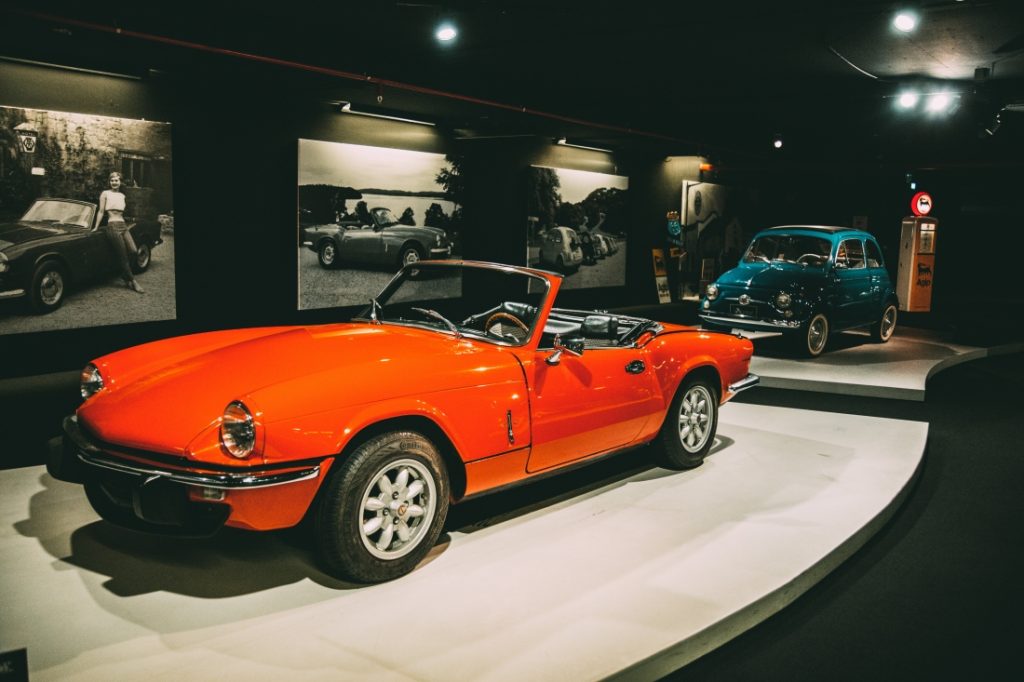 A classic bright orange 1976 Triumph Spitfire on display at the Heydar Aliyev Center's Classic Car Exhibit in Baku, Azerbaijan
