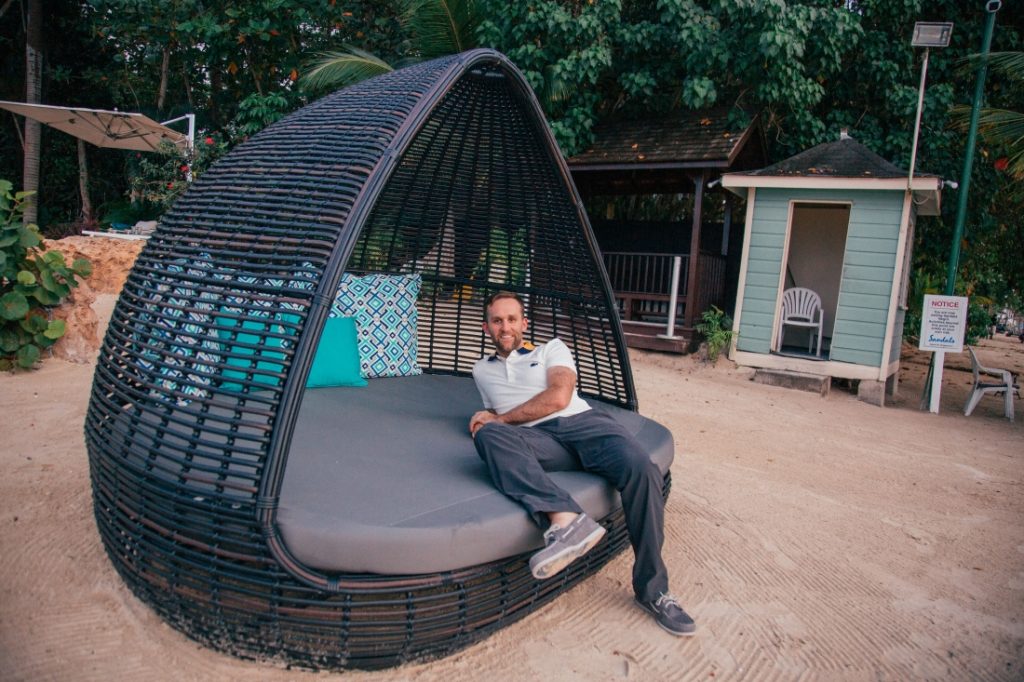 A man sitting on a rattan day bed on the beach.