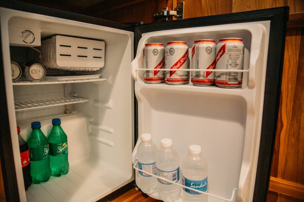The inside of the mini fridge features bottles of Coca Cola, Sprite, Bottled Water and Red Stripe Beer