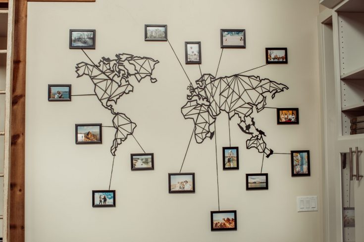 Metal world map laser cut with photo frames and lines pointing to destinations