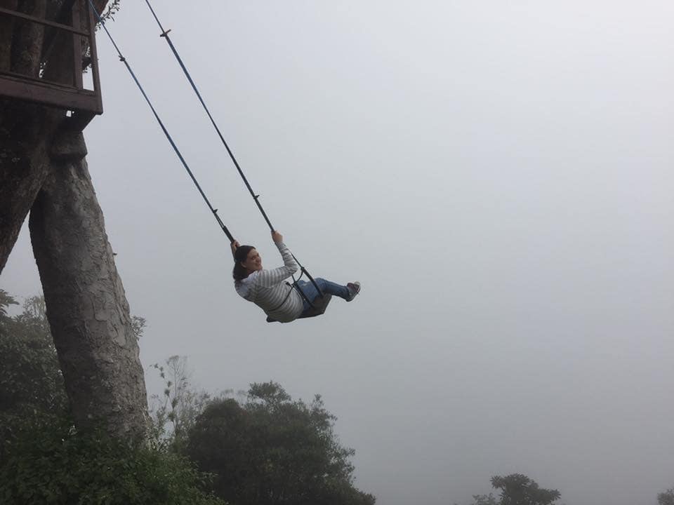A woman swings on swing attached to La casa del árbol, but the gorgeous view is completely obscured by thick fog.