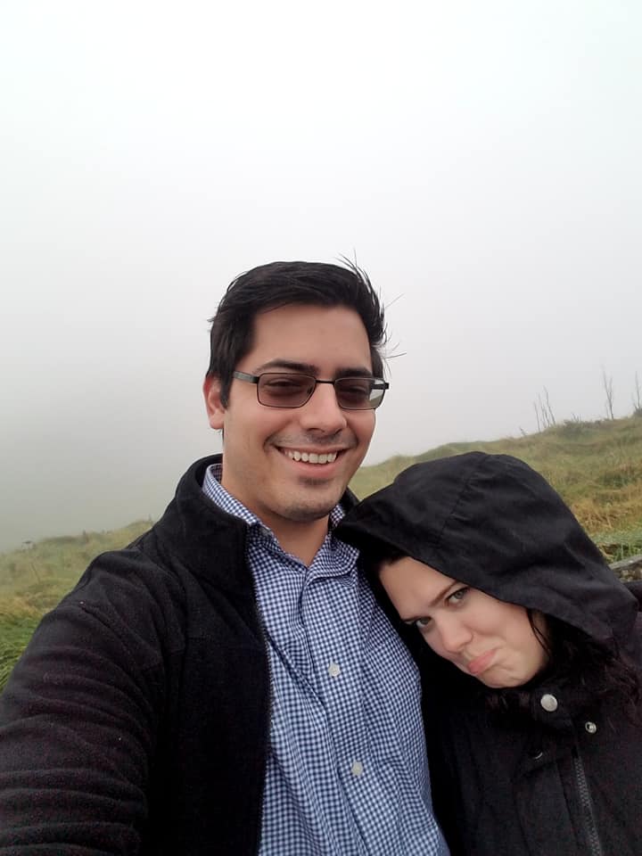 A couple poses at the Cliffs of Moher, which are not visible through thick fog. 