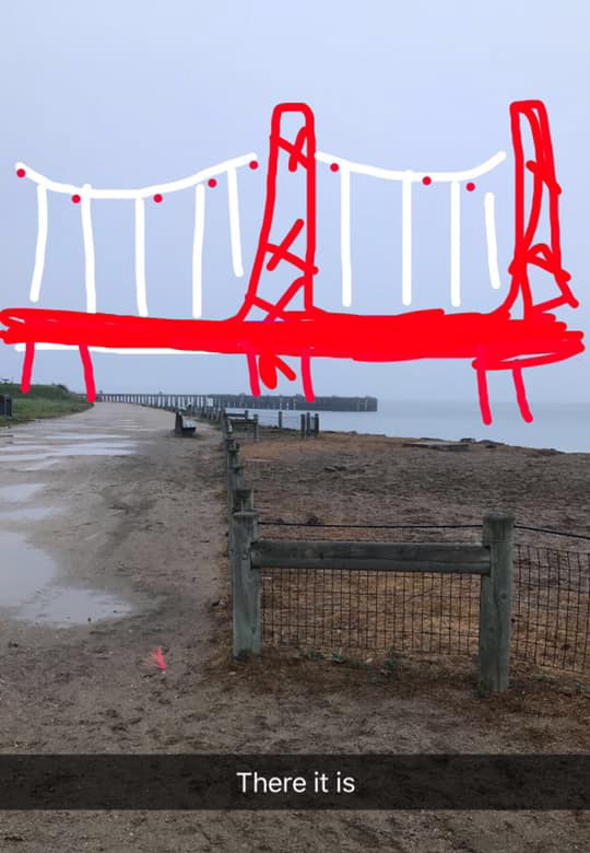 A snapchat image of a beach in San Francisco Bay and a crude red and white line drawing of where the Golden Gate Bridge should be, but it's obscured by fog.