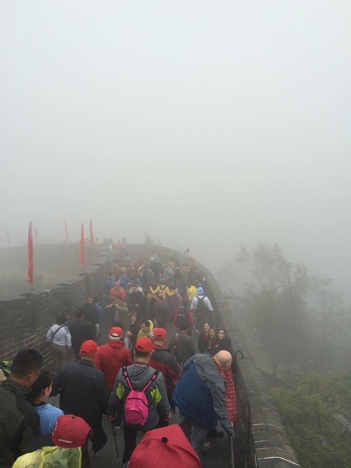 A foggy photo of tourists packed onto a section of The Great Wall of China on a rainy, misty day.