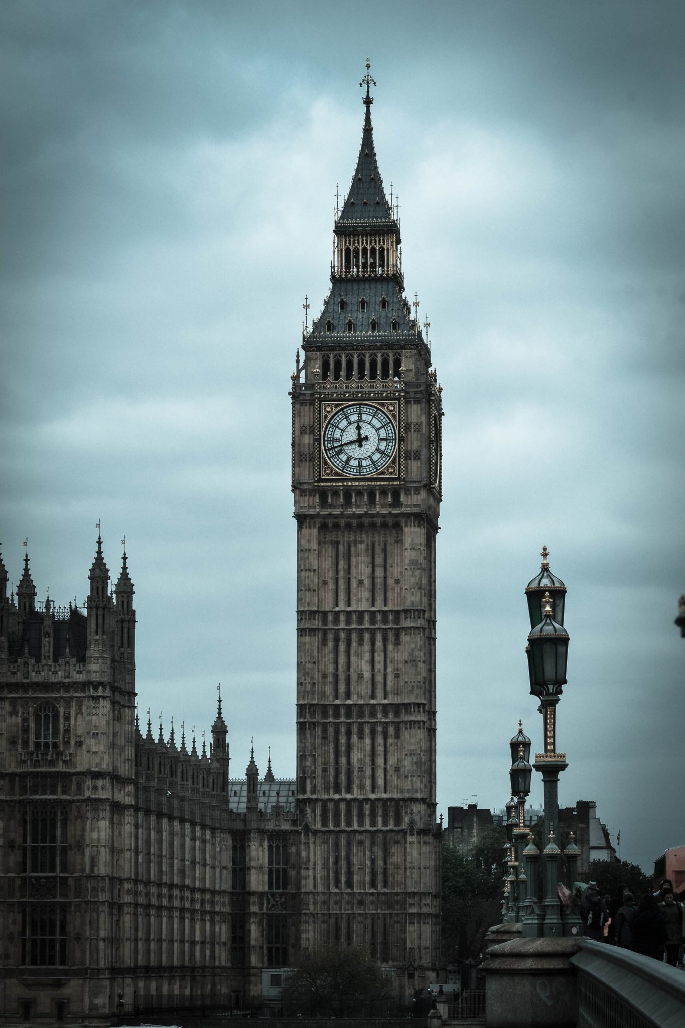 An image of Big Ben and the Parliament building in London. The iconic clocktower stands against a cloudy sky, and the image is filtered to give it a dark, hazy tone.