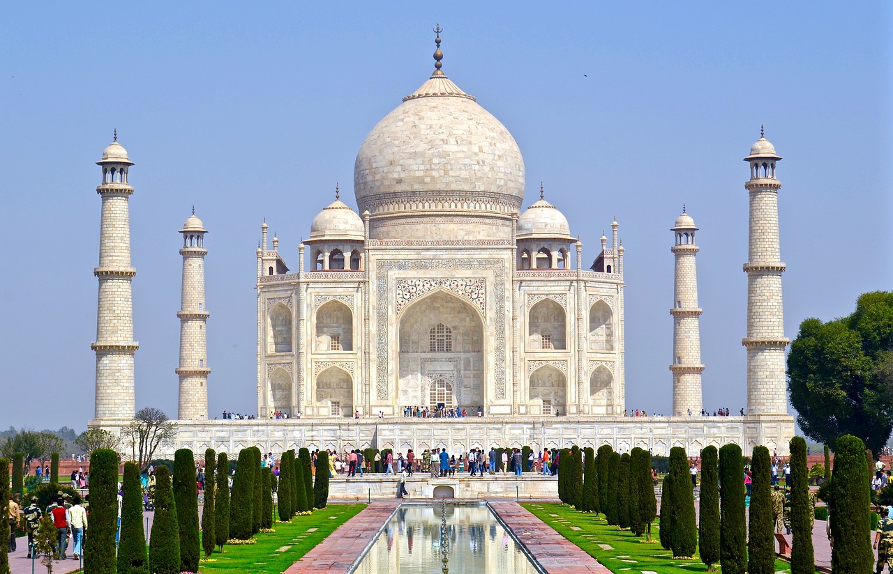 A professional photo of the Taj Mahal and courtyard in front of the giant building. The blue sly is crystal clear.