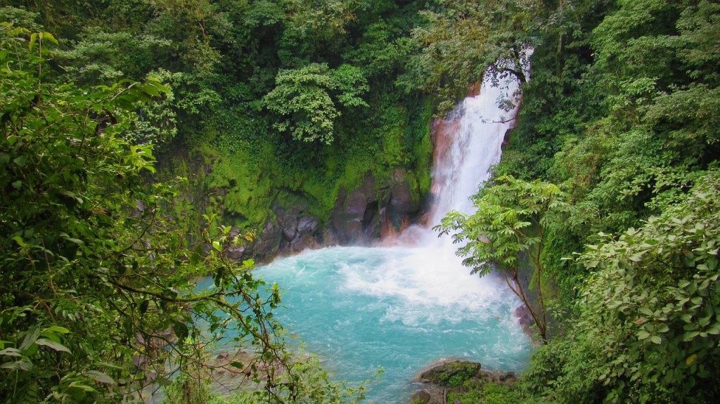 A professional photo of Rio Celeste, a majestic waterfall in the forest of Costa Rica, with crystal blue water surrounded by lush greenery.