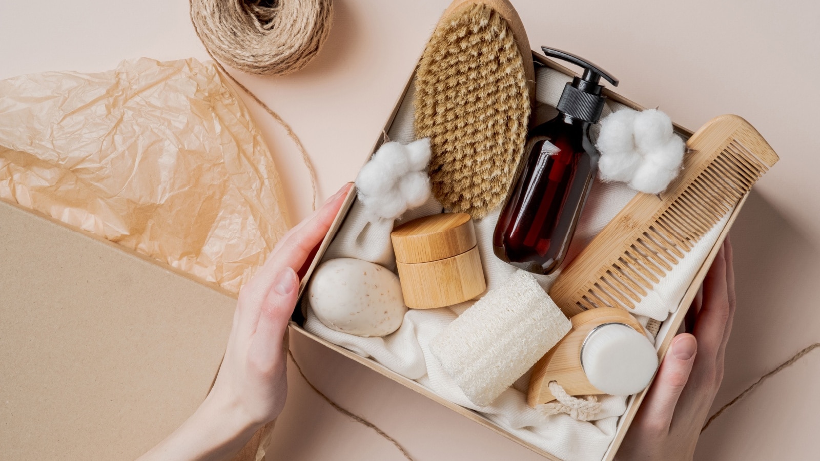 Beauty subscription Box preparation. Female hands holding gift box with natural skincare products, body brush, shampoo, soap, moisturizer.