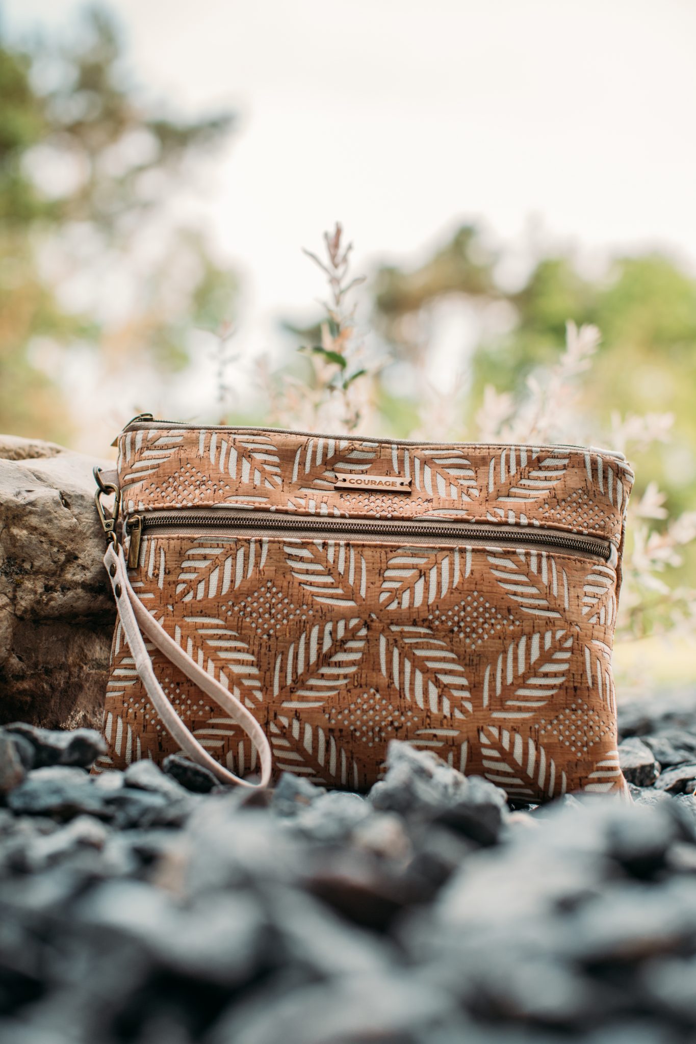 A closeup image of the Carry Courage INVENTOR tablet travel bag -- a clutch made from sustainable cork fabric with a tropical leaf pattern across the bag.