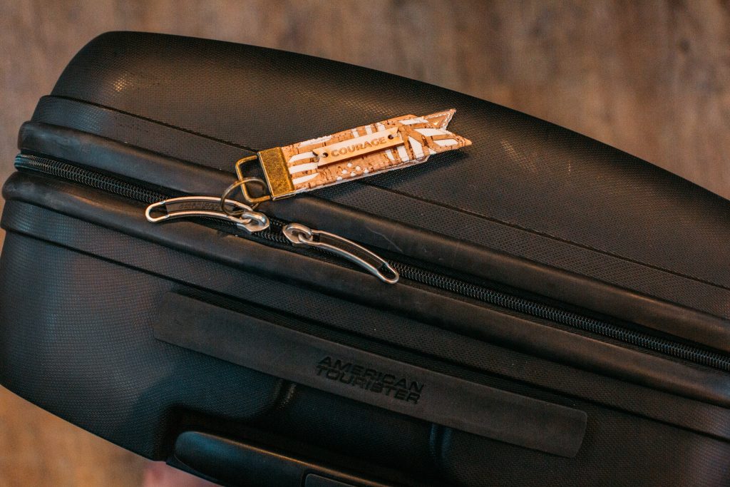 EXPLORER Keychain Luggage Tag on a black suitcase.
