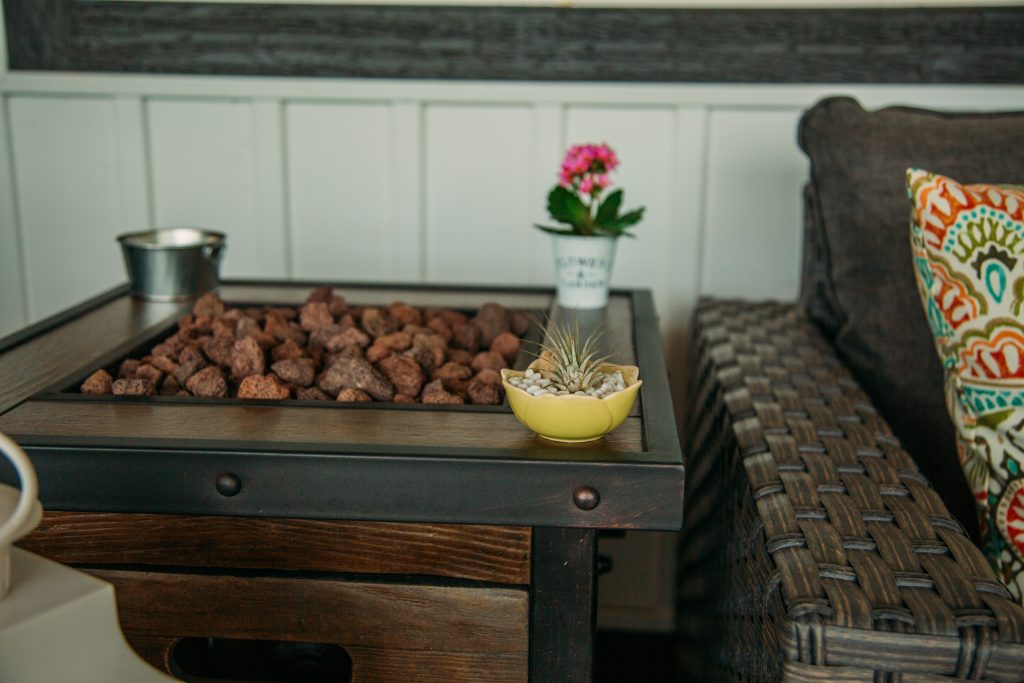 A small air plant rests on the corner of a side table, in a small yellow planter.