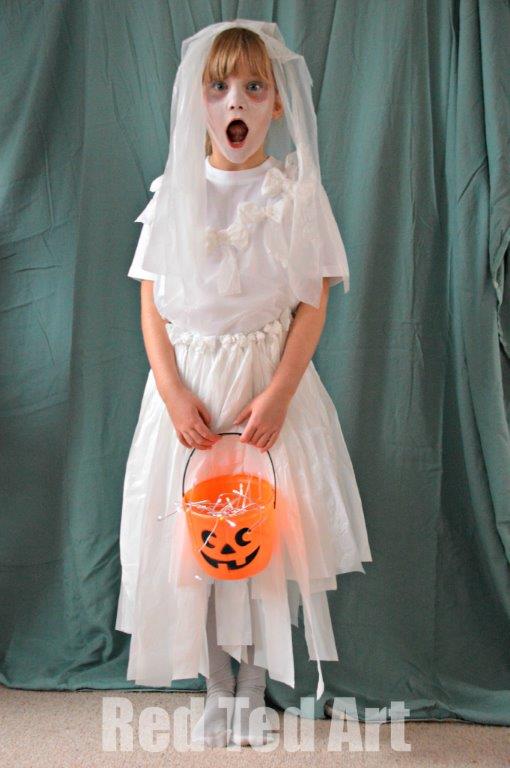A little girl is dressed in a ghost bride costume -- a white tissue paper skirt and veil paired with a white shirt and white tights.