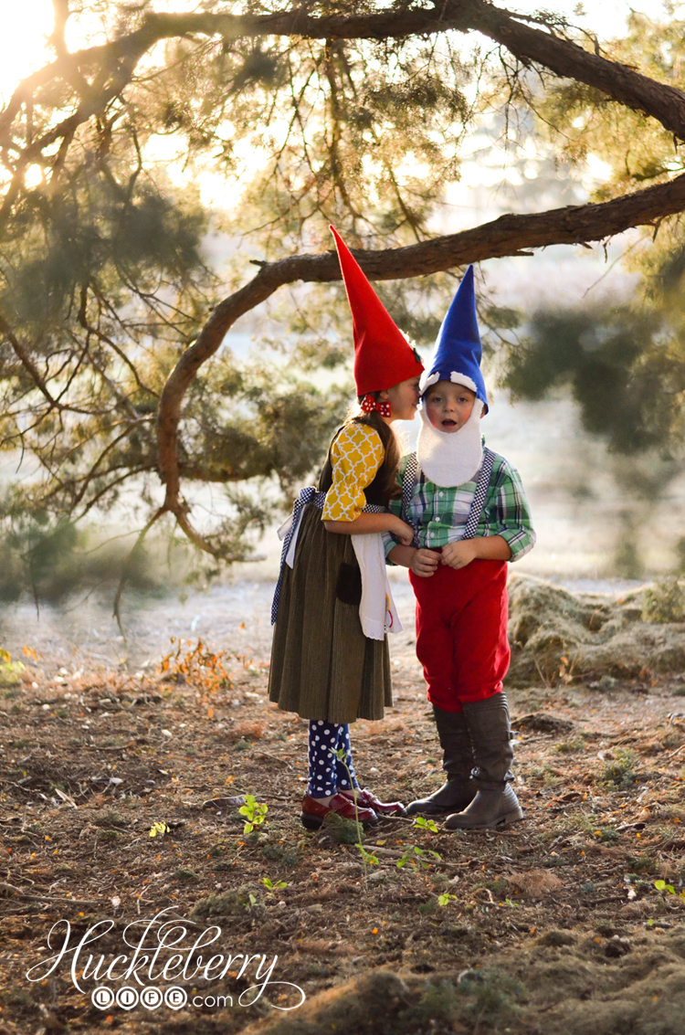 Two young kids stand outside under a tree, dressed in DIY garden gnome costumes.