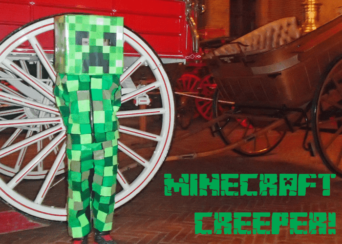 A little boy is dressed as a Minecraft Creeper, a DIY halloween costume made from squares of green and black papers, meant to look pixilated.