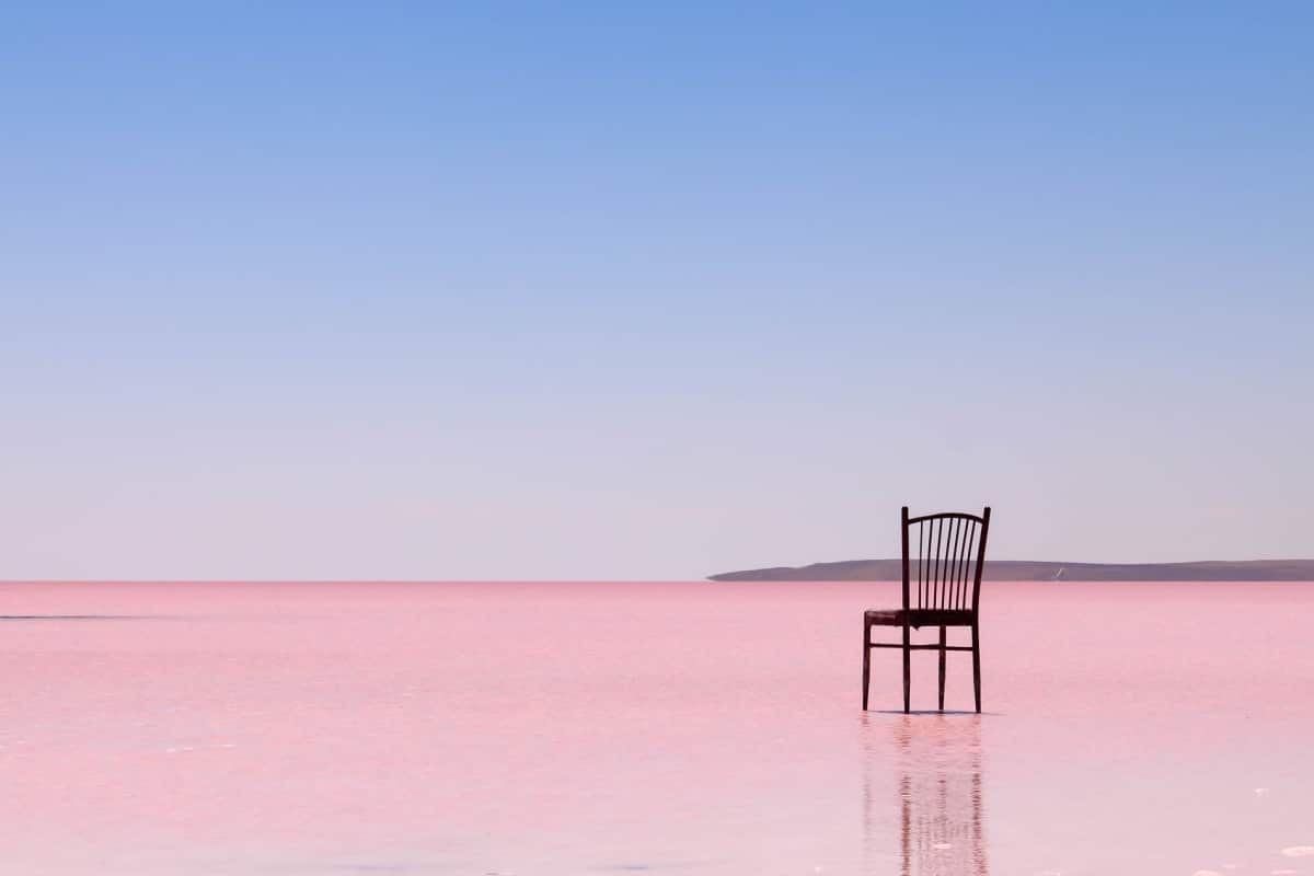 A chair with no people on the pink salt lake in front of a minimalist background