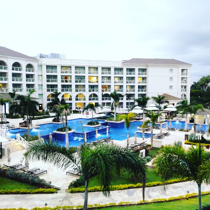 An aerial image overlooks the sprawling pool area at the Hyatt Zilara resort in Montego Bay, Jamaica. A giant pool sits in the center of the grounds, surrounded by lounge areas, plenty of trees, and a walking path.