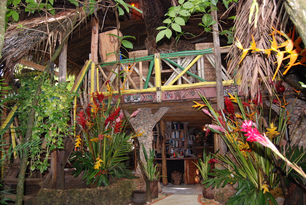 A tropical style treehouse bar and restaurant at the Great Huts Eco Resort in Jamaica. Tropical foliage, trees, and greenery hides the façade of the building.