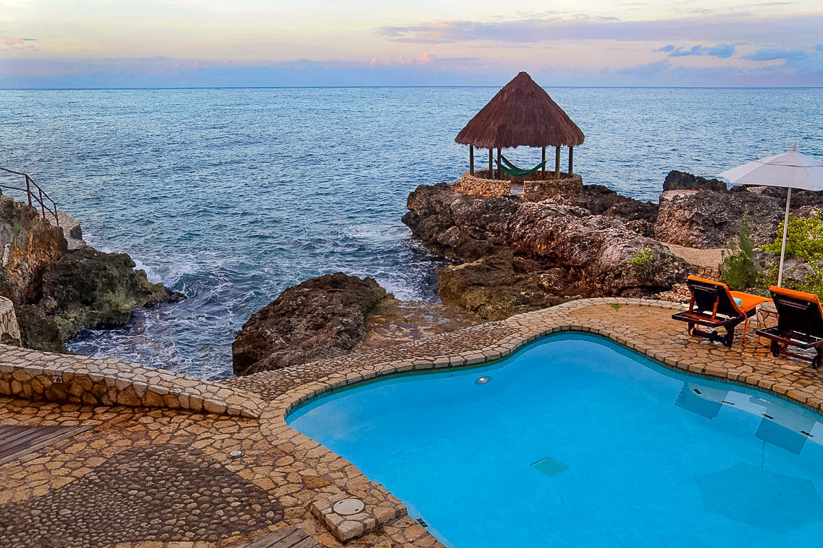 The view from the pool at Tensing Pen Resort in Negril, Jamaica. The private cobblestone paved pool overlooks the ocean at sunset.