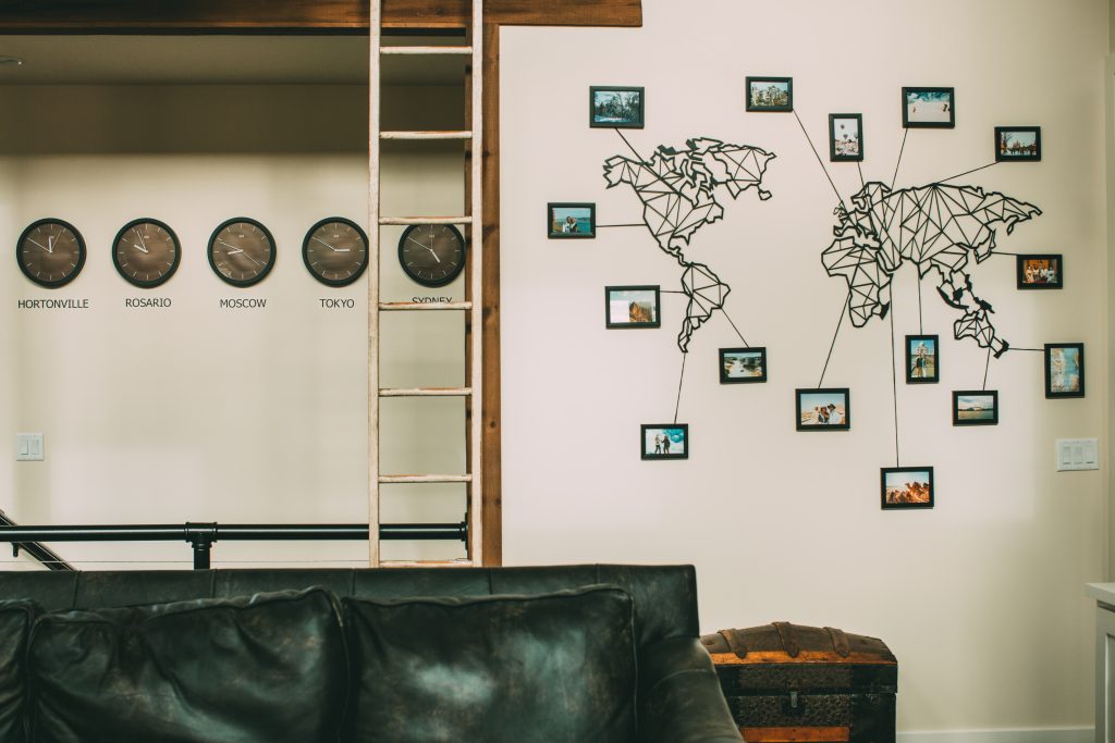 Metal world map laser cut with photo frames and lines pointing to destinations + time zone clocks wall