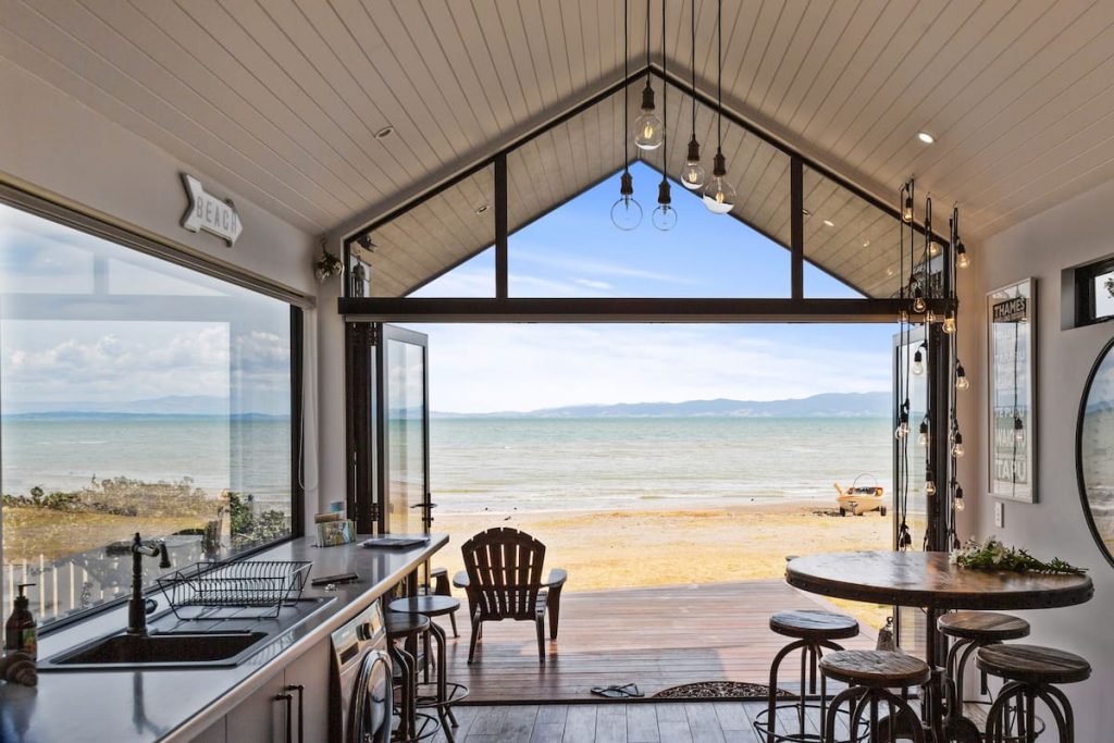 Beachfront Retreat Airbnb with open glass doors directly onto the beach on a sunny day