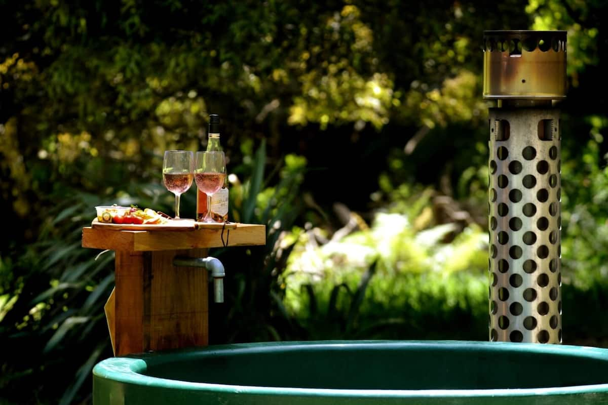 Outdoor hot tub with a cheeseboard and 2 glasses of wine next to it