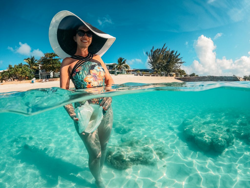 A woman in a swimsuit and sun hat in clear water.