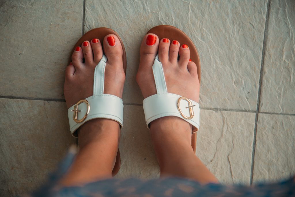 Close up of Lindsey's white sandals with a gold buckle