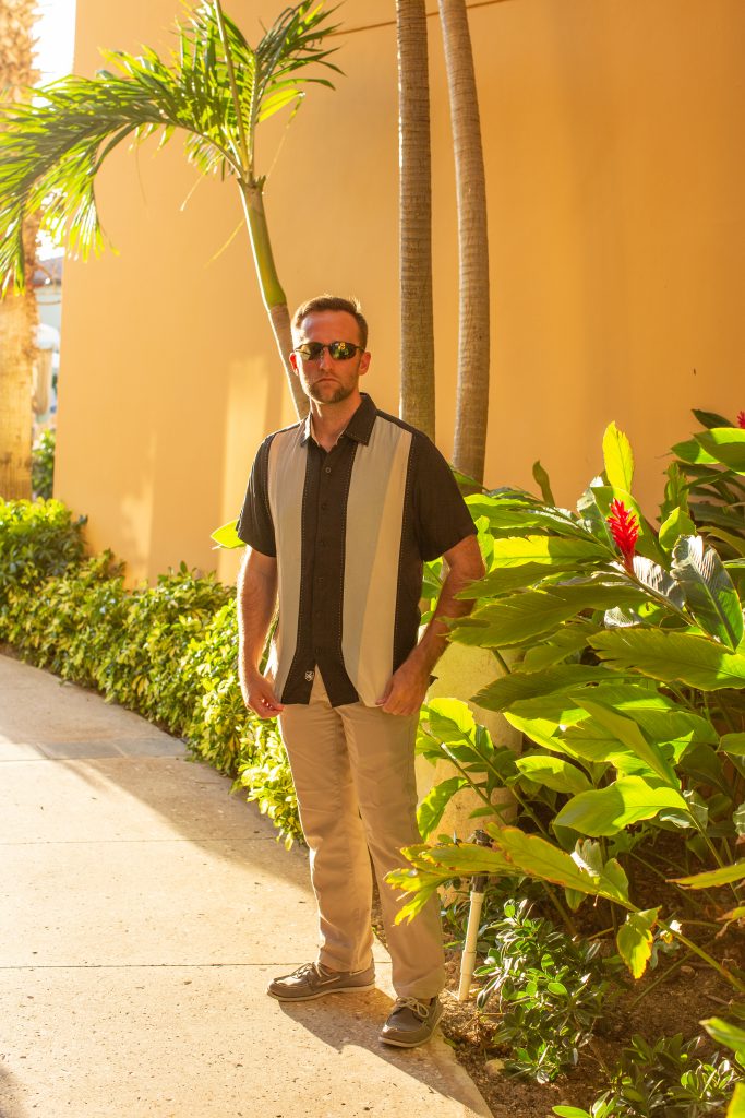 A man standing next to a palm tree.