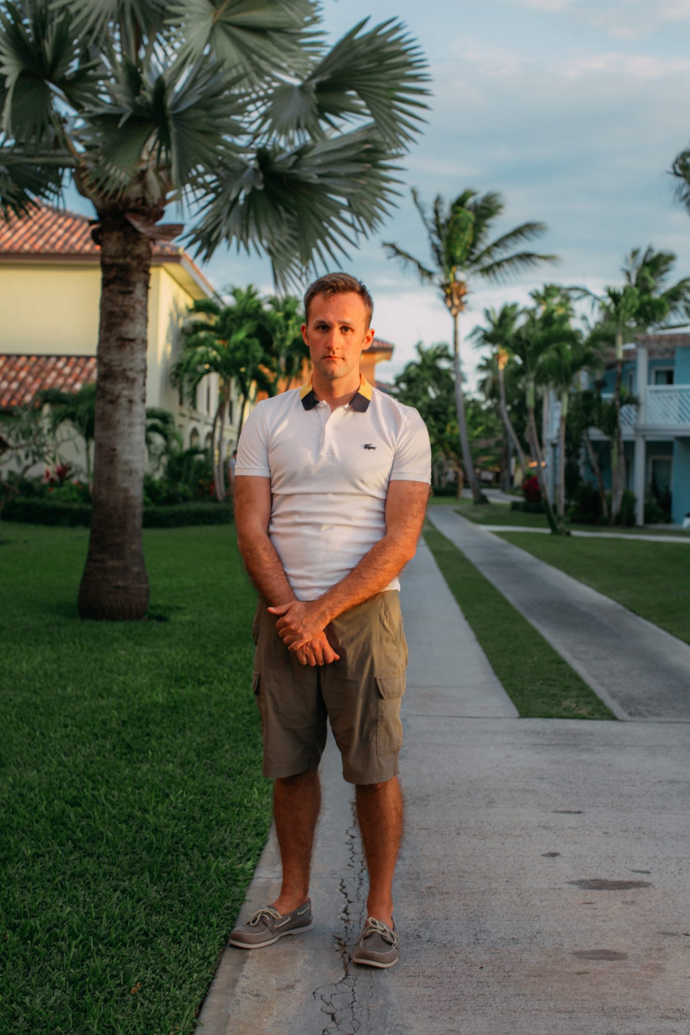 A man standing on a sidewalk in front of palm trees.