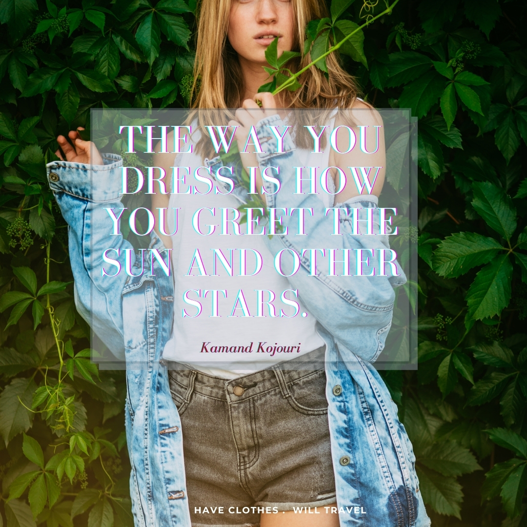 A young woman poses in front of a wall of green leaves and vines. She's wearing a casual outfit of shorts with a white tank top and and oversized denim jacket. Text over the image says, The way you dress is how you greet the sun and other stars. - Kamand Kojouri"