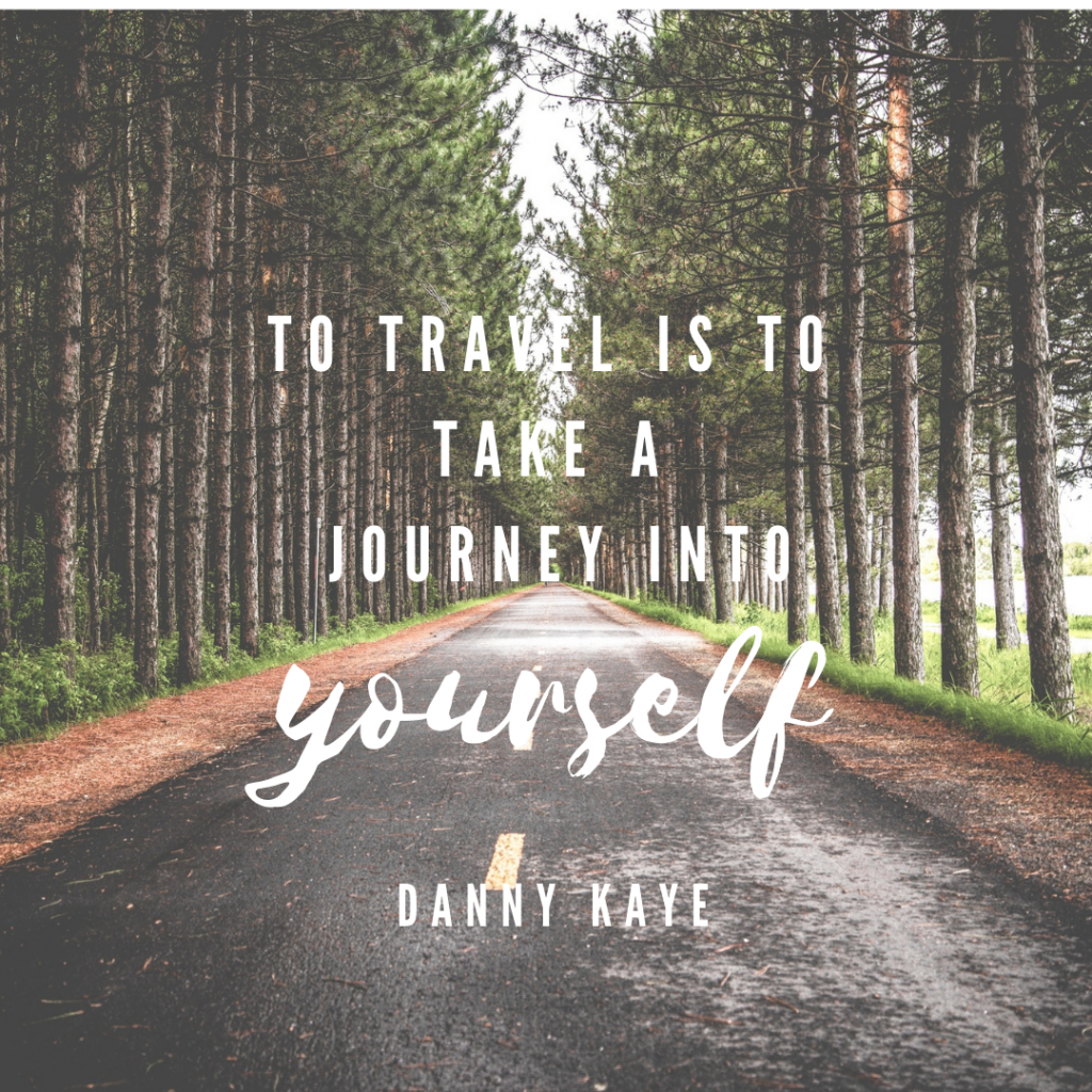 An empty road lined on either side by a forest of tall pine trees. White text over the image reads "To travel is to take a journey into yourself. - Danny Kaye"
