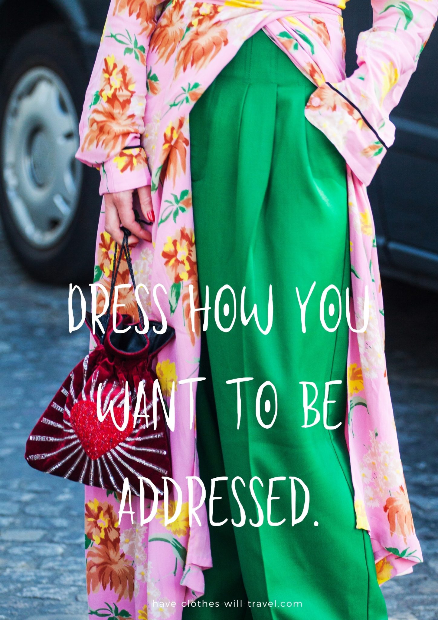 A photo of a woman's lower body, showing a colorful pink and orange floral dress paired with bright green pants and a flashy red statement handbag. White text over the image says, "Dress how you want to be addressed."