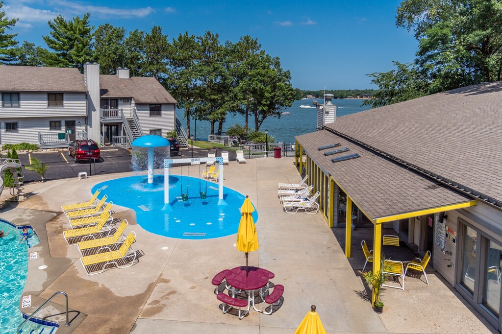 A look at the outside pool area at Lake Delton condo rentals in the Wisconsin Dells. The condos have a view of the lake, a splash pad for kids, lounge chairs, and a kid-friendly pool.