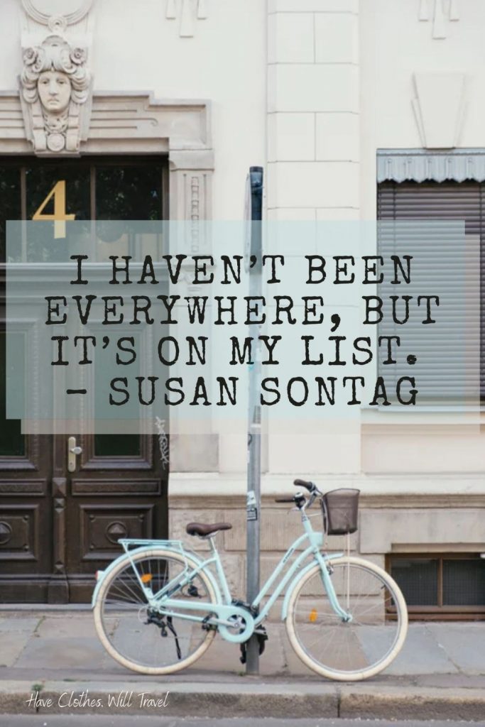 A vintage bicycle rests against a sign post on a city street. Black text over the image reads, "I haven't been everywhere, but it's on my list. - Susan Sontag