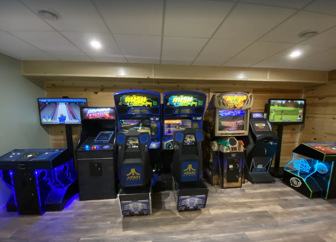 An arcade-worthy game room with multiple gaming consoles located in the basement of a large Wisconsin Dells rental home.