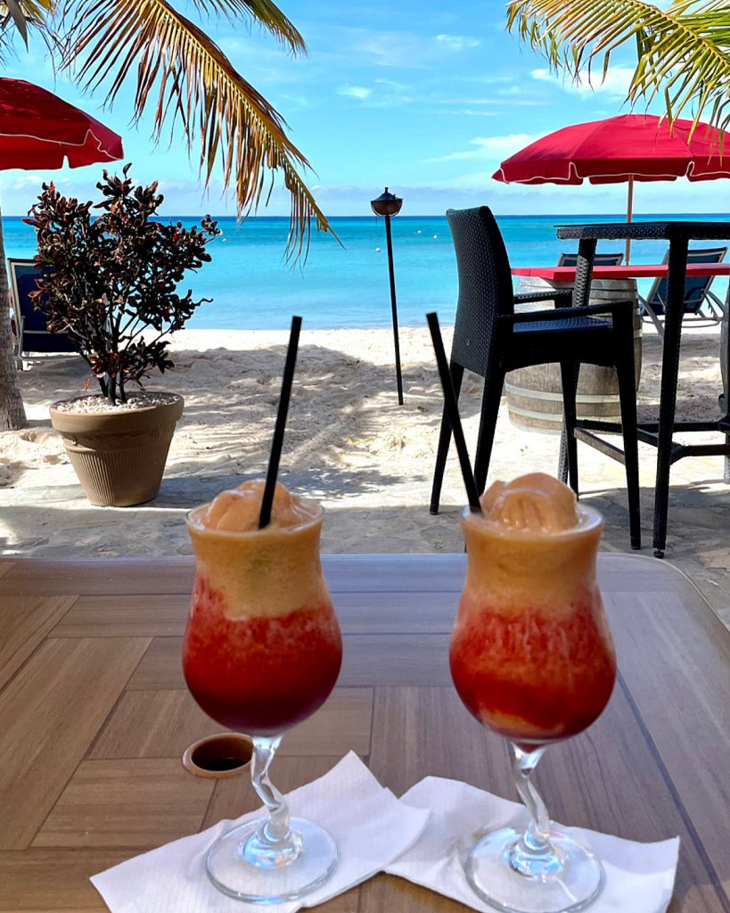 Two drinks on a table next to a beach.in Turks and Caicos.