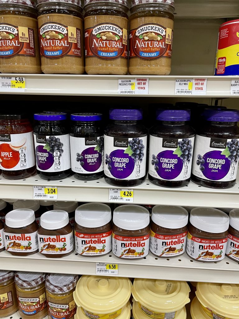 A grocery store shelf with peanut butter and jam with prices in Turks and Caicos.