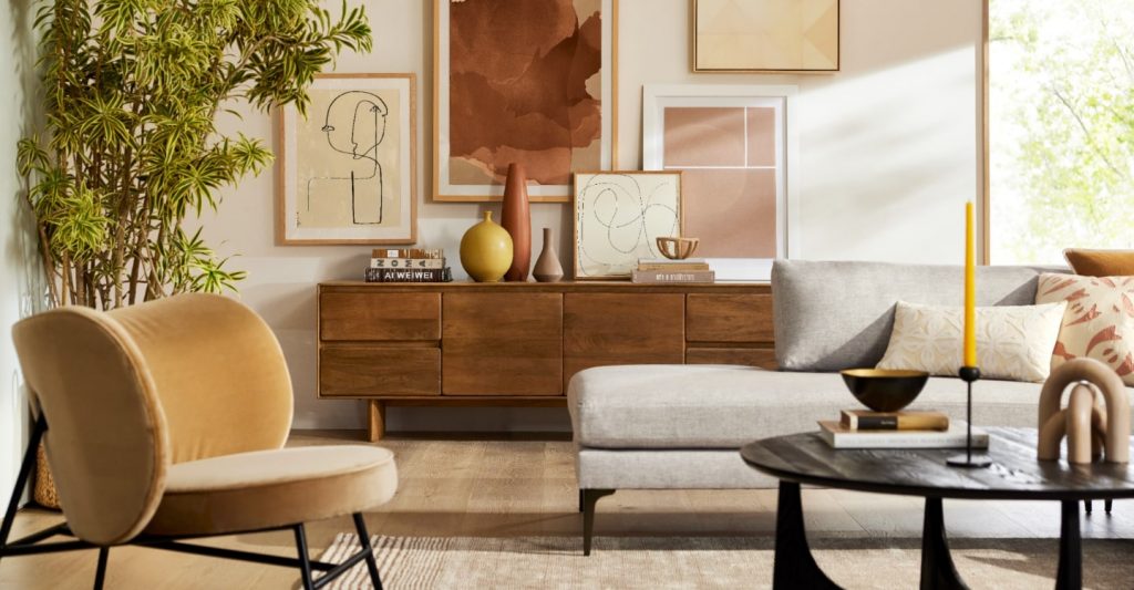 A mid-century modern decorated room with peg leg sofa and chair and dresser