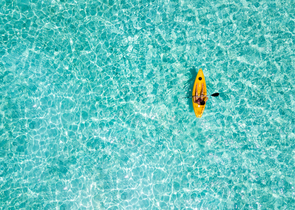 An aerial view of a person kayaking in the ocean.